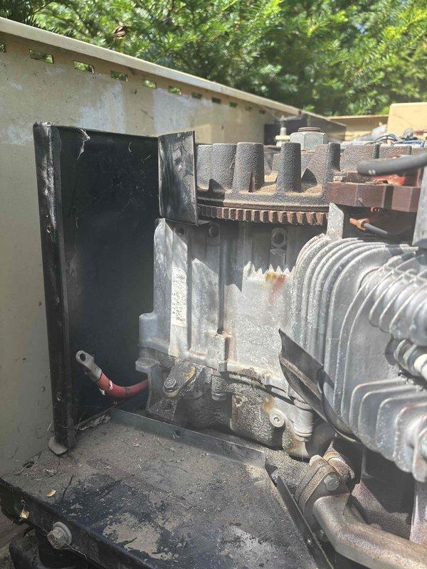 Responded to service call for non-operational Generac generator approximately 10 years old. Upon arrival, performed visual inspection of unit with enclosure access panel removed to assess internal components including engine assembly, fuel system, and electrical connections. Documented current condition of generator system showing weathered exterior housing and mechanical components with signs of age and environmental exposure. Photographed internal configuration including Generac engine unit with cooling fan assembly, cylindrical fuel tank component, and associated electrical wiring and control systems for diagnostic reference and service documentation purposes.