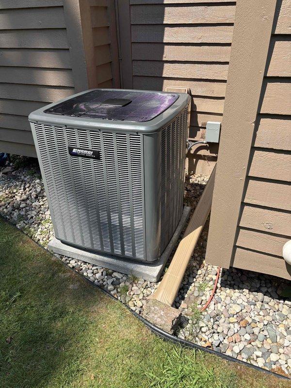 Complete HVAC system replacement performed at residential property. Removed existing air conditioning condenser unit and installed new outdoor condensing unit on concrete pad with proper stone base for drainage and stability. Unit positioned against exterior wall with adequate clearance for airflow and service access. Installed copper refrigerant line set and electrical disconnect box, securing all components to building exterior with appropriate mounting hardware.

Interior installation included new Comfortmaker furnace system in mechanical room, professionally mounted with proper clearances. Connected silver-gray supply and return ductwork to furnace plenum. Installed white PVC condensate drain lines and venting with proper primer application at all joints. Routed electrical conduit and refrigerant lines from outdoor condenser to indoor air handler. Verified all electrical connections at disconnect box and ensured proper voltage supply to equipment.

System startup procedures complet