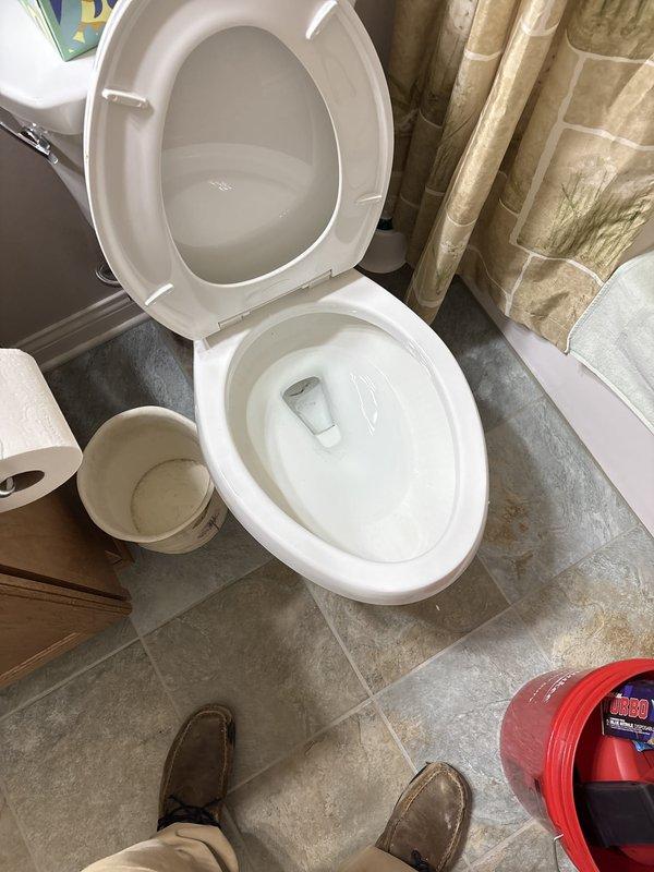 Responded to a plugged toilet in a residential bathroom where the homeowner was unable to clear the blockage. Upon arrival, assessed the white porcelain toilet and surrounding area. Successfully cleared the obstruction using professional drain cleaning equipment. Verified proper flush operation and drainage flow upon completion. Documented the work site with photographs showing the toilet, bathroom fixtures, and stone-look tile flooring for service records.
