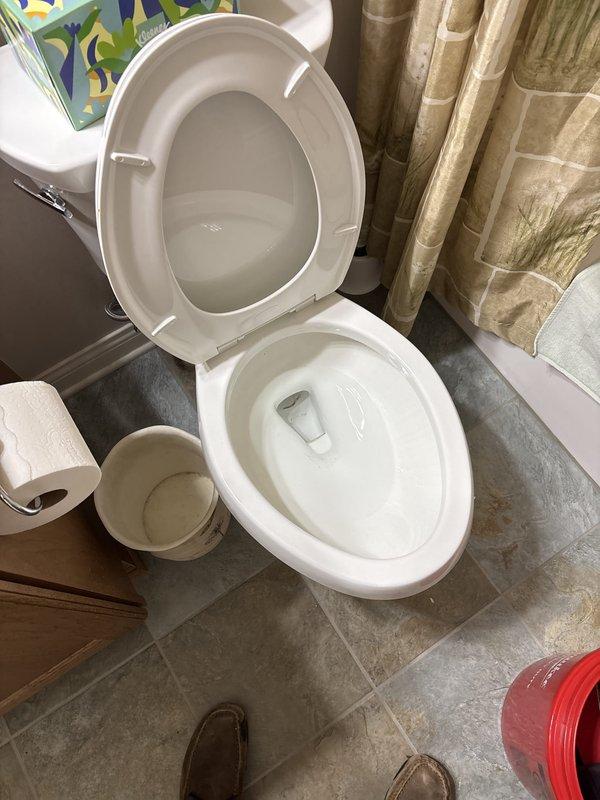 Responded to a plugged toilet in a residential bathroom where the homeowner was unable to clear the blockage. Upon arrival, assessed the white porcelain toilet and surrounding area. Successfully cleared the obstruction using professional drain cleaning equipment. Verified proper flush operation and drainage flow upon completion. Documented the work site with photographs showing the toilet, bathroom fixtures, and stone-look tile flooring for service records.