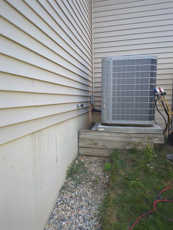 Completed full HVAC system installation including new furnace and air conditioning condenser unit. Outdoor AC unit positioned on concrete pad against building exterior with proper clearances maintained. Installed and secured refrigerant lines with insulation, routed along exterior wall using mounting brackets. Connected electrical wiring and service gauges for system startup and testing. Unit placed on gravel bed for drainage and leveling. System commissioned and verified operational parameters within manufacturer specifications.
