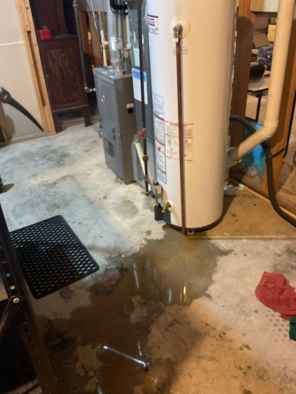Performed AC tune-up on 29-year-old Air Quest system. Upon arrival, customer reported recent part replacement followed by water leakage. Investigation revealed significant water pooling on basement floor around HVAC equipment and water heater, with moisture accumulation on galvanized ductwork indicating condensation issues. Inspected all plumbing connections, drainage lines, and duct system for source of leak. Documented extensive water damage on concrete floor and moisture patterns on metal ductwork surfaces.