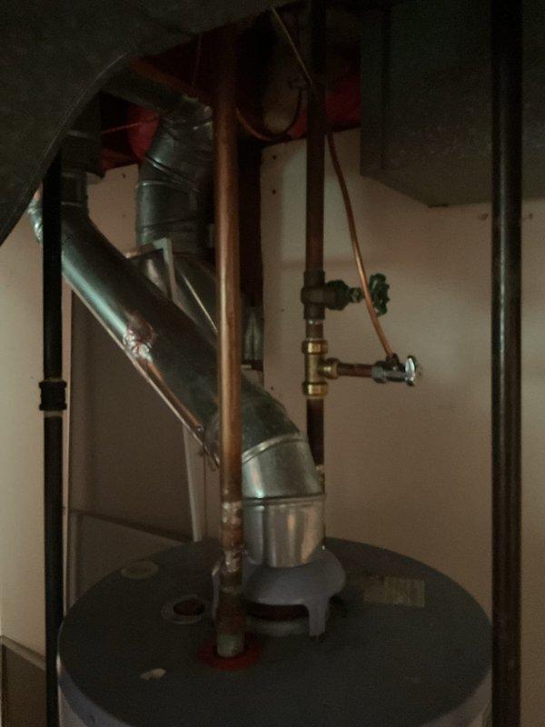 Responded to service call for failed gas water heater that would not light pilot, leaving residence without hot water. Inspected 15-year-old conventional tank-style gas water heater and confirmed unit failure. Evaluated existing installation including copper supply lines, gas connections, venting system, and pressure relief valve configuration. Documented current setup with photographs showing plumbing connections, ductwork, and surrounding utility space layout. Provided consultation and prepared comprehensive estimates for two replacement options: tankless on-demand water heater installation and traditional tank-style gas water heater replacement to allow comparison of both solutions.