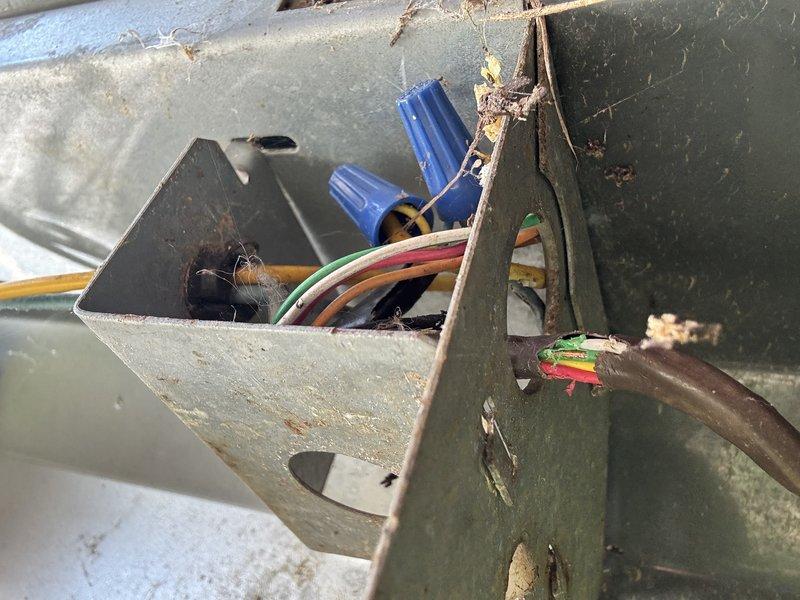 Responded to no-cooling call where customer reported discovering chewed wires and evidence of rodent intrusion. Upon inspection, found electrical junction box and interior compartment with multiple wire connections showing signs of rodent damage, accumulated debris, organic material, and general deterioration. Documented existing conditions with photographs showing compromised wiring insulation, dirt accumulation, and nesting materials within the unit requiring immediate attention to restore safe operation.