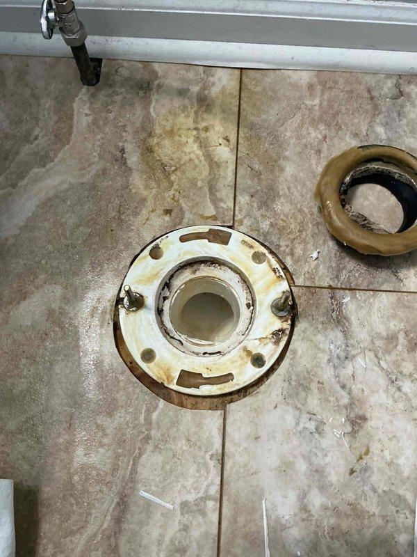 Responded to callback for toilet seal failure on previously installed unit. Removed toilet to expose failed wax ring and flange assembly showing signs of water and urine leakage onto tile flooring. Inspected flange for damage and proper mounting, noting discoloration and staining on surrounding floor tiles. Replaced wax ring seal, reinstalled toilet, and tested for proper seating and leak-free operation to prevent further floor damage.