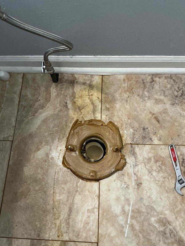 Responded to callback for toilet seal failure on previously installed unit. Removed toilet to expose failed wax ring and flange assembly showing signs of water and urine leakage onto tile flooring. Inspected flange for damage and proper mounting, noting discoloration and staining on surrounding floor tiles. Replaced wax ring seal, reinstalled toilet, and tested for proper seating and leak-free operation to prevent further floor damage.