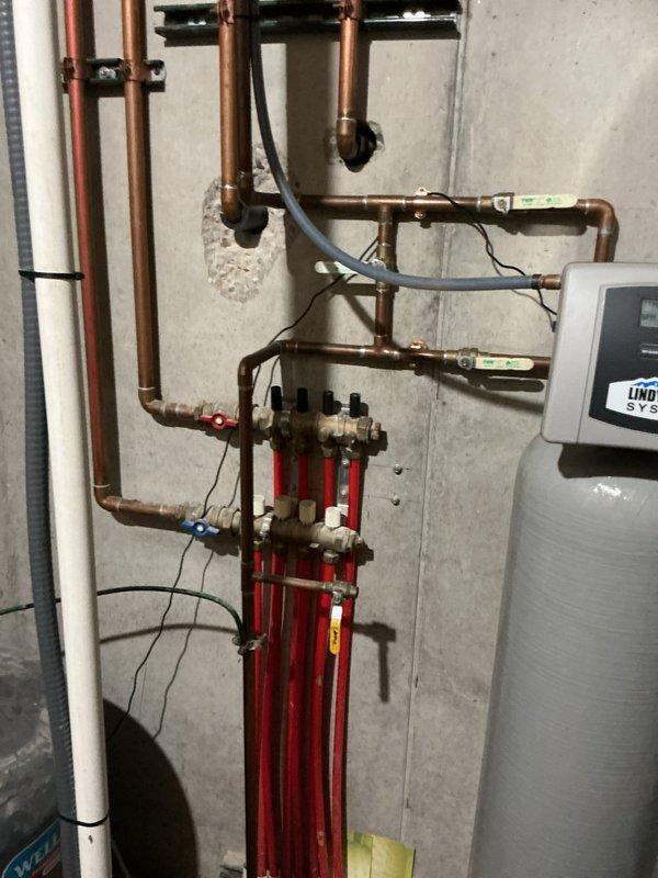 Responded to water quality concerns by conducting comprehensive assessment of existing water treatment infrastructure. Documented hydronic heating system with manifold assembly, copper distribution piping network, and water heater installation in mechanical room. Inspected and photographed water filtration system consisting of dual-tank configuration including softener unit with digital control head and secondary treatment tank with bypass valving and copper supply connections. Verified operational status of equipment and provided client with photographic documentation of current system condition for quality evaluation purposes.