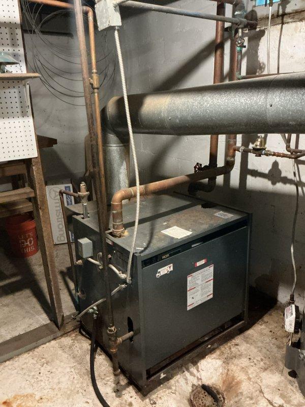 Completed comprehensive plumbing inspection of residential property including mechanical room and under-sink installations. Documented boiler system with copper supply piping, flexible venting connections, and associated HVAC ductwork in basement utility area. Inspected kitchen/bathroom sink drain assembly featuring standard P-trap configuration with PVC piping and braided supply lines, confirming proper installation and operational condition of all visible plumbing components.