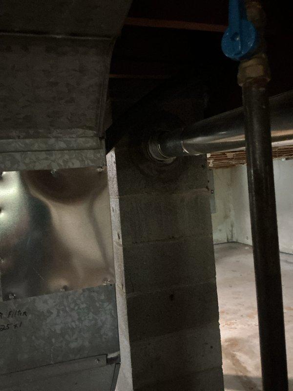 Responded to no hot water condition affecting entire residence. Upon inspection, found 11-year-old AO Smith water heater in basement utility area with significant dust accumulation and age-related wear. Unit located in unfinished basement space with proper venting through existing flue system connected to horizontal ductwork. Documented existing installation showing cylindrical tank-style heater with metallic flue pipe, red-handled valve connection, and manufacturer specification plate. Assessed basement infrastructure including concrete block walls, exposed floor joists, and concrete flooring suitable for replacement installation. Provided estimate for water heater replacement due to unit failure and age exceeding typical service life expectancy.