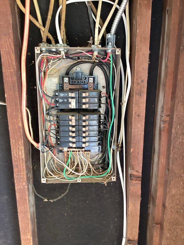 Responded to customer request for electrical panel evaluation due to fire hazard concerns. Conducted thorough inspection of aging residential circuit breaker panel mounted in wooden wall frame. Panel exhibited signs of wear consistent with older electrical installation, including surface discoloration and dust accumulation on beige metal enclosure. Assessed wiring configuration including multiple copper cables, white insulated wires, and colored conductors entering from top and bottom of panel. Examined circuit breaker arrangement in two vertical columns with older style black and tan switches. Documented condition of main disconnect components, wire connections with twist-on connectors, and flexible metal conduit. Photographed panel installation and surrounding wooden framing for estimate preparation. Provided assessment findings and recommendations for necessary repairs or panel replacement to address potential safety concerns.