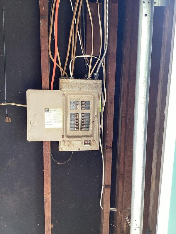 Responded to customer request for electrical panel evaluation due to fire hazard concerns. Conducted thorough inspection of aging residential circuit breaker panel mounted in wooden wall frame. Panel exhibited signs of wear consistent with older electrical installation, including surface discoloration and dust accumulation on beige metal enclosure. Assessed wiring configuration including multiple copper cables, white insulated wires, and colored conductors entering from top and bottom of panel. Examined circuit breaker arrangement in two vertical columns with older style black and tan switches. Documented condition of main disconnect components, wire connections with twist-on connectors, and flexible metal conduit. Photographed panel installation and surrounding wooden framing for estimate preparation. Provided assessment findings and recommendations for necessary repairs or panel replacement to address potential safety concerns.