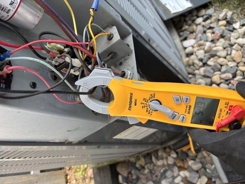 Responded to no cooling complaint on residential air conditioning system. Upon arrival, performed electrical diagnostics on outdoor unit using digital multimeter and clamp meter. Measured voltage at contactor and capacitor connections, reading 6.69V at control board wiring and 5.9A at compressor circuit. Tested all electrical components including contactor, capacitor, and associated wiring connections. Documented findings with photographs showing voltage and amperage readings during diagnostic process. System evaluated for proper electrical supply and component functionality to identify root cause of no cooling condition.