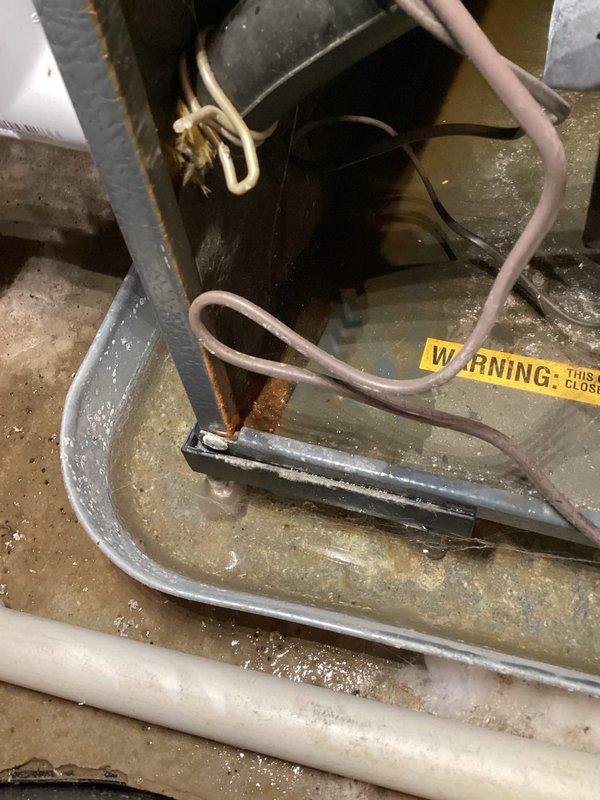 # ASTU-AC Super Tune-up Completed

Performed comprehensive super tune-up service on a 22-year-old air conditioning system located in a basement utility area with significant water damage and standing water present. The unit exhibited extensive corrosion on copper refrigerant lines, rusted pipe connections, and deteriorated metal components throughout, indicating prolonged moisture exposure. 

Conducted full system inspection despite challenging environmental conditions, including flooded workspace with murky standing water surrounding equipment. Examined motor assembly, electrical connections, and wiring harnesses which showed signs of age but remained functional. Documented heavily corroded copper elbow joints and pipe connections with reddish-brown oxidation, along with rust-stained condensate pan and metal framework.

Inspected all electrical components including multi-colored wire bundles, ground wire connections, and control box housing. Verified proper wire routing and connection