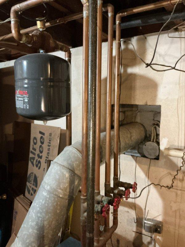 Responded to client request for estimate to extend hydronic heating system to sunroom addition. Assessed existing boiler system and photographed current mechanical room setup, including copper piping configuration, Amtrol expansion tank, and distribution manifold. Evaluated sunroom access point from main living area to determine routing requirements for new heating zone.