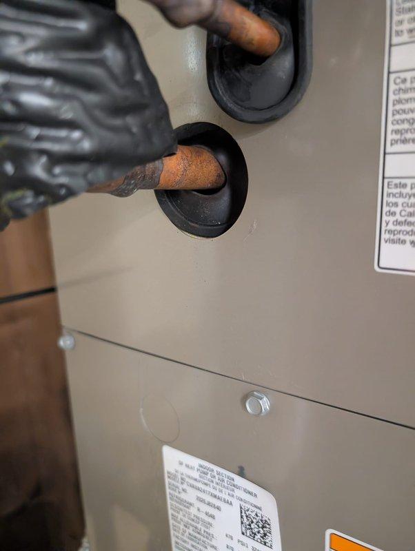 Responded to inspector correction request for suction line grommet installation and insulation adjustment. Installed missing grommet on suction line penetration through equipment panel to prevent condensate dripping onto furnace below. Pushed line insulation tight to evaporator coil to ensure proper seal and drainage control. Documented completed corrections with photos showing proper grommet installation and sealed penetration points on copper refrigerant lines.