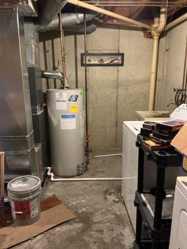 Completed rental inspection of water heater in basement mechanical room as requested. Documented water heater condition, brand identification, and age determination through photographic evidence. Unit is a standard residential gas-fired water heater with copper supply piping and proper venting, located adjacent to HVAC equipment in concrete block foundation area.