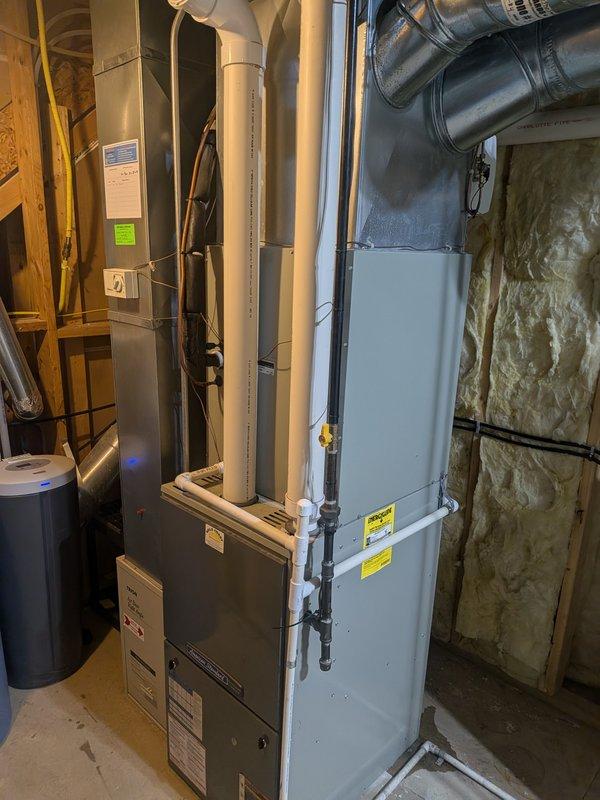Responded to no cooling complaint on 19-year-old Allegiance AMSTD system with inadequate cooling on second and third floors. Performed system inspection and diagnostics of furnace and ductwork in basement mechanical room. Documented equipment condition with photos showing furnace unit, water heater, PVC condensate drainage, metallic ductwork, and insulated wall cavity. Advised customer that age of system and performance issues may require replacement unit versus repair options based on findings.