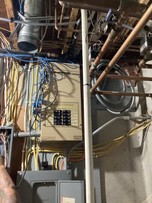 Completed comprehensive ECI-Electrical Club Inspection of residential electrical system, documenting main service panel configuration with Guardian brand distribution panel containing multiple circuit breakers and associated branch circuit wiring. Photographed exposed electrical infrastructure in basement utility area, including panel interior showing extensive yellow, red, white, and black conductor routing, secondary distribution panel, and overhead cable management systems for maintenance documentation and safety compliance verification.
