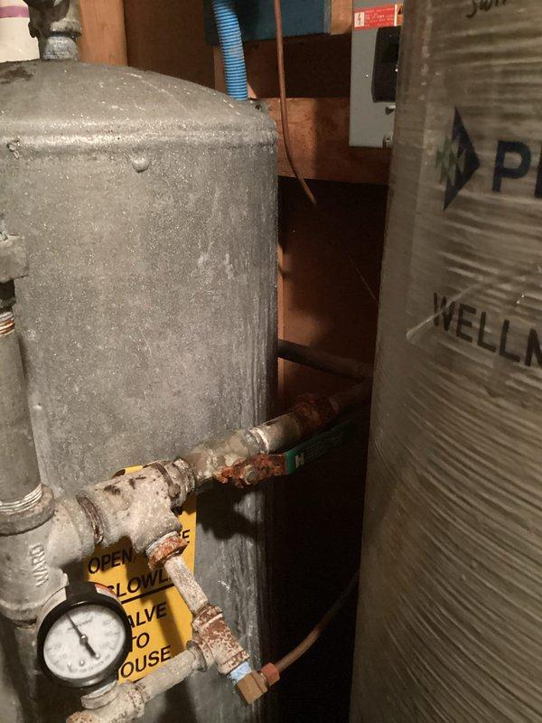Completed water softener system replacement in residential basement utility area. Removed existing aged water softener unit showing signs of corrosion and wear, then installed new white cylindrical water softener tank with digital control head unit featuring programmable display and multi-button interface. Connected unit to existing copper supply lines using professional soldered joints and appropriate fittings. Verified all plumbing connections for proper flow and tested system operation to ensure digital display and control functions working correctly. Disposed of old equipment per standard procedures.