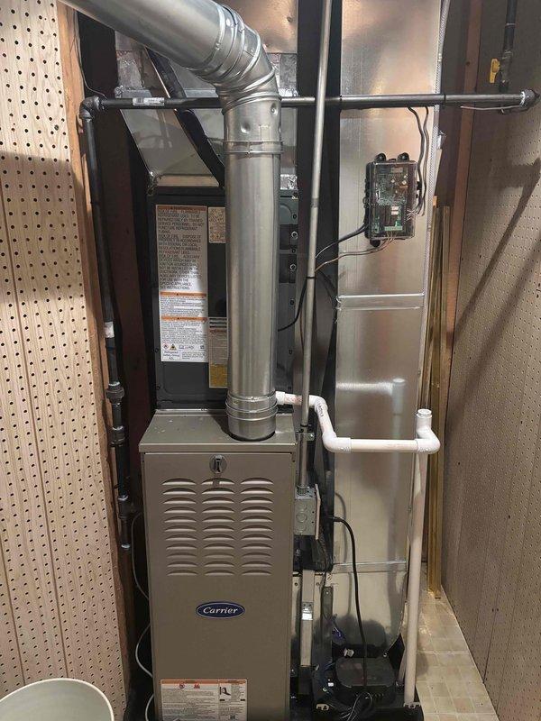 Completed full HVAC system replacement including outdoor condensing unit and indoor air handler. Installed new Carrier furnace system in basement utility area with proper ductwork connections, electrical disconnect, and PVC condensate drain lines. Mounted exterior condenser unit on concrete pad with electrical conduit run and disconnect box properly secured to exterior wall, ensuring all components meet manufacturer specifications and local code requirements.