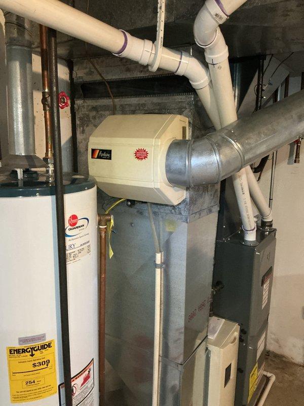 Responded to water leak complaint at furnace system in side-by-side condo. Upon inspection, identified active leak at furnace valves while system maintained heating capability. Documented equipment condition and leak location with photographs showing HVAC system, water heater, humidifier unit, and associated piping in mechanical room. No immediate safety concerns observed and heating function remained operational at time of service.