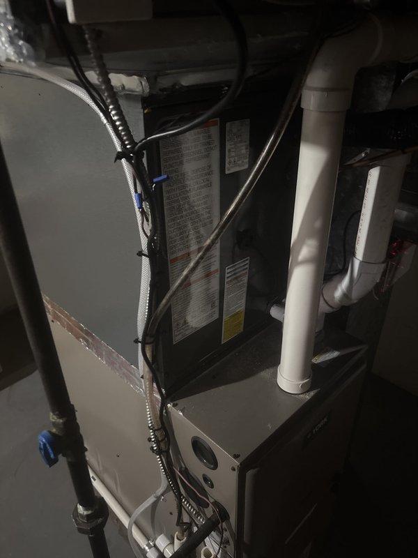 Completed full HVAC system installation including indoor air handler unit positioned in basement mechanical room and outdoor condensing unit mounted on concrete pad at building exterior. Installed new refrigerant lines, electrical connections, condensate drainage, and PVC venting system per manufacturer specifications. System tested and verified operational with all safety labels and documentation properly affixed to equipment.