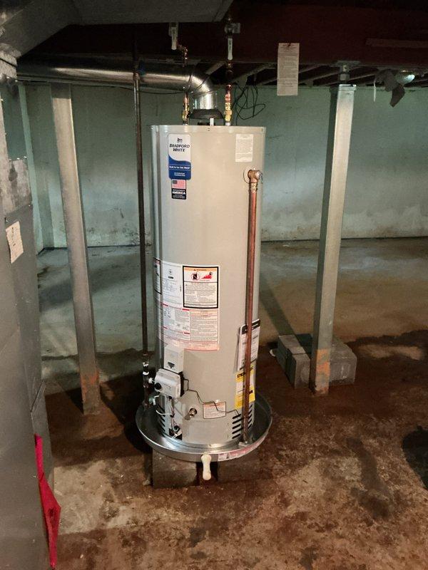 Completed installation of a 40-gallon Bradford White natural gas atmospheric vent water heater in basement location. Unit was properly positioned on metallic base plate, with all copper supply and discharge piping connected per manufacturer specifications and local code requirements. Gas line connection, temperature and pressure relief valve, and venting system were installed and tested for proper operation and safety compliance.
