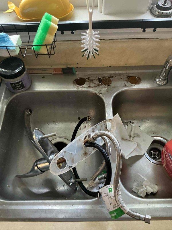 Responded to multiple plumbing issues in 90-year-old residence including slow-draining kitchen sink and lack of hot water at fixture. Inspected under-sink plumbing and identified drainage concerns with existing PVC P-trap configuration. Removed and evaluated kitchen faucet assembly to address hot water delivery issue, documenting condition of stainless steel double-basin sink, supply lines, and water filtration system. Photographed plumbing components, including Waterdrop filtration unit, braided supply lines, and drainage assembly for assessment and recommendations.