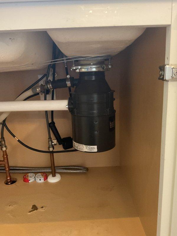 Responded to leaking garbage disposal complaint. Upon inspection, found 1/2 horsepower InSinkErator disposal unit installed under kitchen sink with active leak. Diagnosed leak source, performed necessary repairs to disposal unit and associated drain connections. Verified all mounting hardware, drain flange seal, and discharge connections were properly secured. Tested unit operation and confirmed leak was resolved with no further water discharge observed.