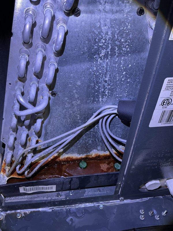 Completed annual cooling maintenance and tune-up on 15-year-old residential air conditioning system. Upon inspection, discovered evaporator coil heavily frosted with ice accumulation, indicating restricted airflow or potential refrigerant issue. Examined condensate drain system with white PVC piping in mechanical space, confirmed proper drainage function. Documented frost buildup on coil surface and noted minor corrosion on copper components within unit. System requires follow-up evaluation to determine root cause of icing condition, which may include low refrigerant charge, dirty air filter, or blower motor malfunction.