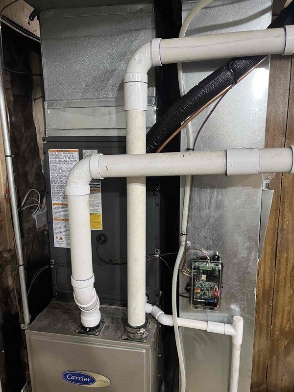 Completed full air conditioning system replacement including outdoor condensing unit and indoor air handler. Installed new Carrier HVAC equipment with proper refrigerant line connections, electrical disconnect, condensate drainage system with PVC piping configuration, and integrated ductwork connections. System tested and verified operational upon completion.
