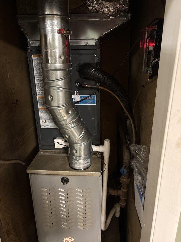 Completed full air conditioning system replacement at residential property. Removed existing outdoor condenser unit and installed new gray AC condenser on concrete pad with proper electrical connections including new disconnect switch and conduit routing to existing meter panel. Indoor installation included integration with existing furnace system, installation of new evaporator coil assembly, and proper refrigerant line connections using black flexible refrigerant lines. Verified all electrical connections meet code requirements with proper wire gauge and secure mounting of junction boxes on exterior wall. Completed condensate drainage system using white PVC piping with appropriate pitch and secured all ductwork with proper hangers and supports. Pressure tested refrigerant lines, evacuated system to proper vacuum levels, and charged unit to manufacturer specifications. Performed full system startup, verified proper airflow across evaporator coil, confirmed correct superheat and subcoo