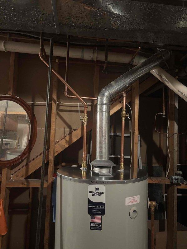 Completed installation of a 75-gallon Bradford White natural gas water heater with 76,000 BTU/hr capacity in basement utility area. Connected copper supply piping with brass fittings, installed galvanized metal flue venting system, and verified proper gas connections at 4.0" water column inlet pressure. Unit tested and operational at 150 psi working pressure with all safety labels and manufacturer specifications visible and compliant.