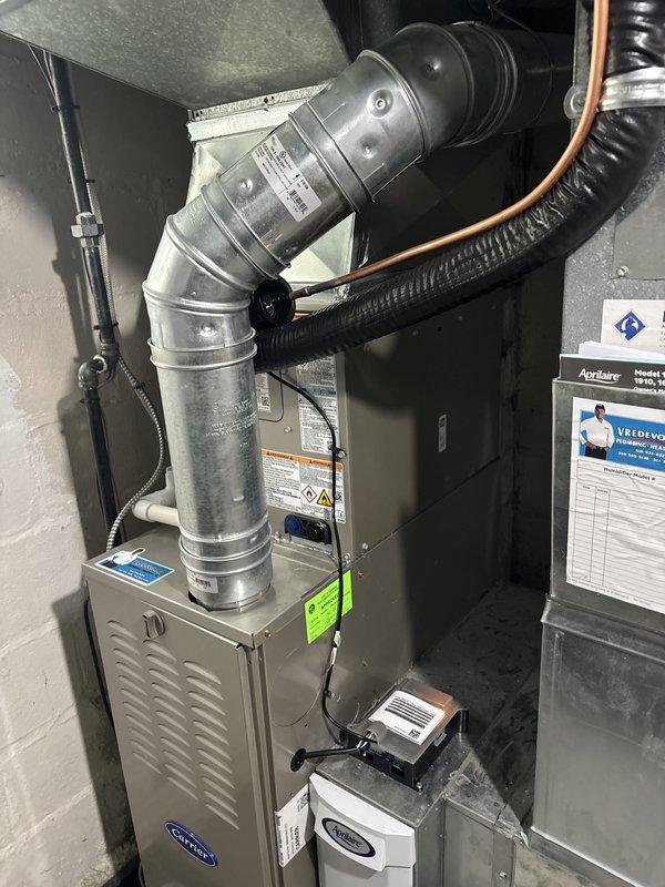 Completed full HVAC system replacement including installation of new Carrier furnace unit in basement utility area with proper ventilation ductwork, refrigerant line routing, and integrated humidifier system. Installed new outdoor air conditioning condenser unit on concrete pad with electrical disconnect box and conduit properly secured to exterior wall. All components tested and operational, documentation completed and posted on-site.