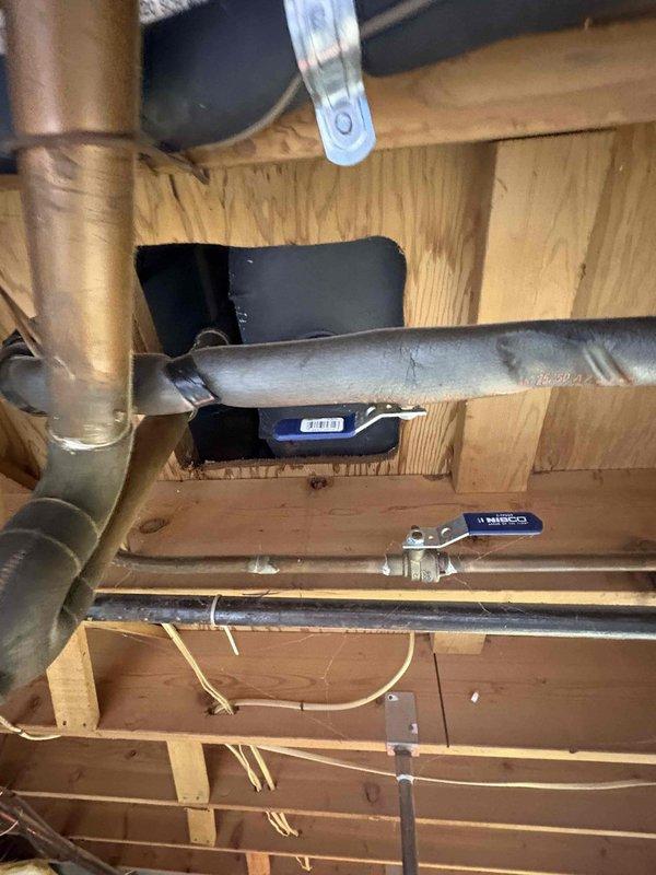 Responded to complaint of gurgling tub drain when toilet flushed and strong acidic odor in 60-year-old home with septic system. Accessed plumbing system through basement/crawlspace to inspect drain and vent piping. Upon investigation, identified venting issue in drain-waste-vent system causing negative pressure when toilet discharged, resulting in gurgling at tub drain and allowing sewer gases to escape into living space. Documented existing plumbing configuration with photos showing copper drain lines, vent pipes, and connection points between fixtures to assess proper venting and drainage flow for this single-bathroom home on septic system.