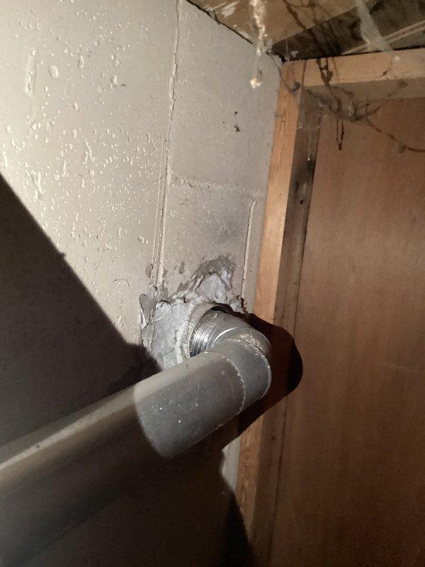 Responded to customer report of leaking water heater and performed comprehensive assessment of existing residential water heater system located in basement utility area. Upon inspection, observed active water staining and discoloration on concrete floor surrounding base of water heater tank, confirming reported leak condition. Documented current installation with beige cylindrical tank, copper supply piping with compression fittings at top connections, and adjacent water treatment equipment. Evaluated plumbing penetrations through walls including galvanized steel piping with rough patching material requiring attention. Photographed equipment condition, leak evidence, and installation configuration to provide accurate estimate for water heater replacement and associated plumbing modifications needed to address the leak and bring installation up to current code standards.