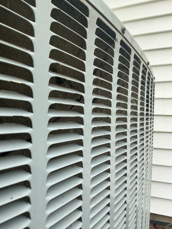 Responded to no cooling complaint on 10-year-old Daikin system affecting entire home. Confirmed unit was running but not producing cold air. Performed diagnostic inspection of outdoor condensing unit, documenting equipment condition and exterior components. Photos captured show outdoor unit with dirty/clogged condenser coil louvers containing significant dust and debris accumulation, restricting proper airflow through the heat exchanger. This contamination prevents adequate heat rejection and reduces system cooling capacity. Verified best contact number for follow-up communication regarding necessary repairs or maintenance to restore proper cooling operation.