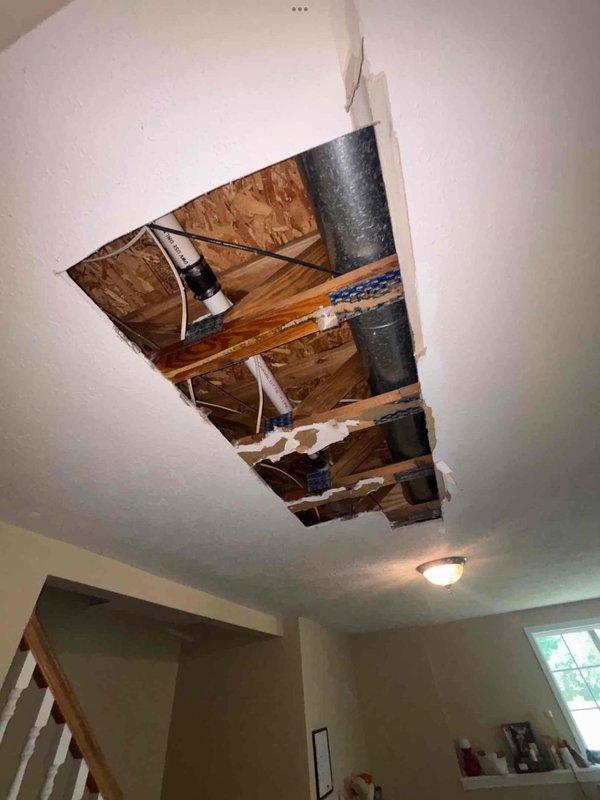 Responded to reported slow leak under kitchen sink ongoing for 3–4 weeks. Upon inspection and customer walkthrough, discovered the issue was not related to kitchen plumbing but originated from HVAC system in attic space above. Accessed attic through ceiling opening to investigate moisture source. Found extensive rust staining and corrosion on air conditioning unit mounting bracket, indicating prolonged moisture exposure from condensation drainage issue. Identified AC condensate drain problem as root cause of suspected leak rather than plumbing system failure. Documented conditions with photographic evidence showing rusted bracket, ductwork configuration, and attic framing. Diagnosed condensation issue affecting 2–3 year old HVAC installation requiring attention to prevent further moisture damage to structure.