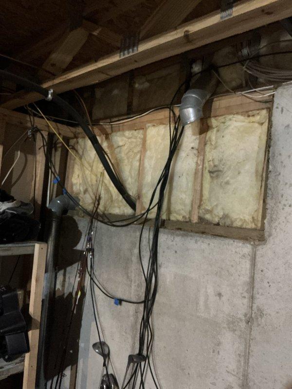 Completed comprehensive sales estimate for furnace and air conditioning system replacement. Existing equipment remains operational but inspection revealed failed heat exchanger in furnace creating hazardous condensation issues in basement area. Exterior AC condenser unit showing significant age-related deterioration with weathering and dirt accumulation on black cylindrical housing. Documented current system configuration including outdoor condensing unit positioned on gravel bed alongside building foundation, utility connections, and basement mechanical room conditions. Assessed unfinished basement space with exposed concrete block walls, wooden ceiling joists, existing ductwork, and electrical infrastructure. Photographed equipment locations, mounting surfaces, and utility routing to support replacement proposal. Provided customer with detailed estimate for new high-efficiency furnace and air conditioning system installation to address failed heat exchanger safety concern and improve
