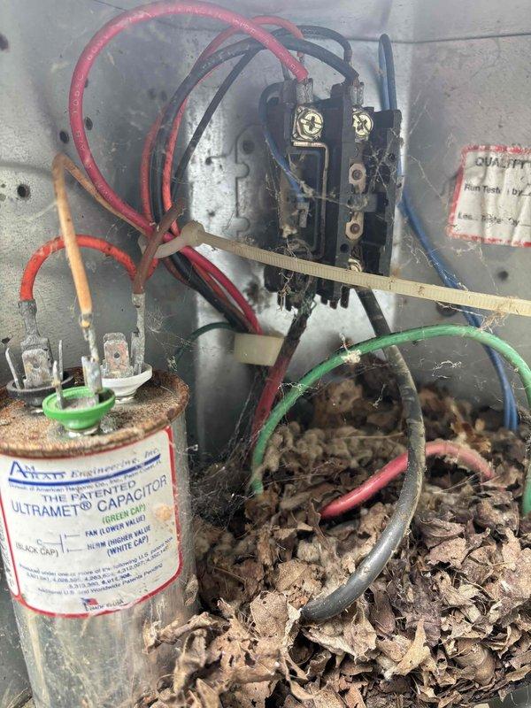 # Cooling System Electrical Failure - North End Unit

Responded to no-cooling complaint on 15-year-old air conditioning unit affecting north end of residence. Upon inspection, discovered extensive electrical terminal corrosion and contamination within outdoor condensing unit. Found severe rust and oxidation on primary electrical connections, compromising circuit integrity. Interior of electrical control panel heavily contaminated with organic debris, nesting material, and plant matter that had infiltrated the enclosure. 

Identified corroded wire terminals and connections at junction box as primary failure point preventing compressor operation. Capacitor and associated wiring also affected by debris accumulation and moisture intrusion. Cleaned electrical enclosure, removed all organic contamination, and replaced deteriorated terminals and corroded connections. Restored proper electrical continuity to control circuit. Verified capacitor function and all wire connections. Sealed enclosur