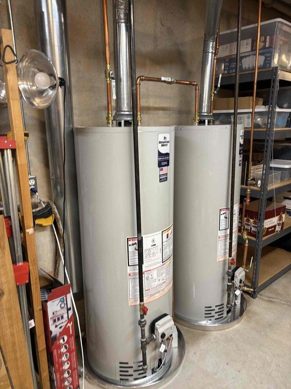 Completed twin water heater installation in basement utility room, installing two 50-gallon natural draft natural gas water heaters positioned side by side. Connected copper supply and discharge piping with brass fittings and valves to both units, installed proper venting through metal ductwork to ensure safe exhaust of combustion gases, and verified all gas connections for leak-free operation. Both water heaters are covered under 6-year parts and 1-year labor warranty, with installation completed per manufacturer specifications and local code requirements.