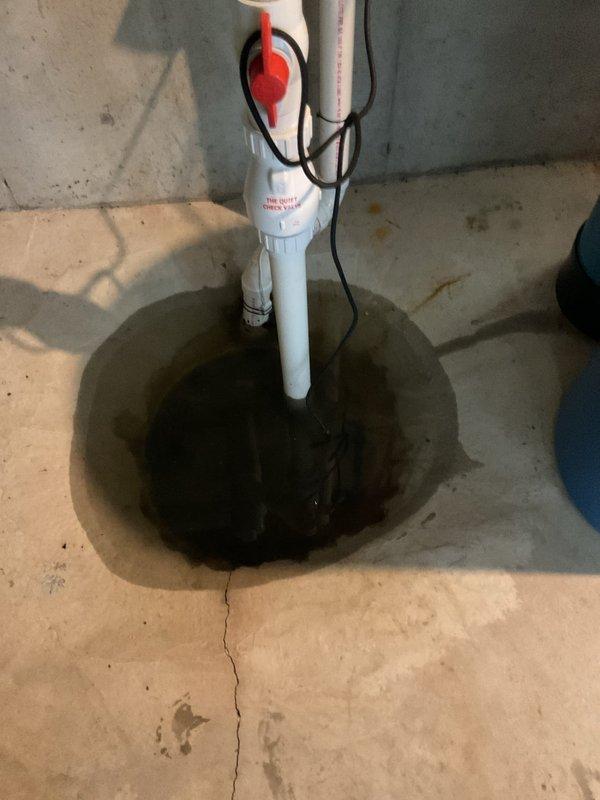 Responded to water leak emergency in basement that triggered EPS system. Inspected sump pump system and surrounding area to identify source of water intrusion. Upon arrival, water had already dried up from previous day's flooding. Examined 7-year-old Carrier HVAC system, including air conditioning unit and furnace, as potential sources of water leak. Documented sump pump pit installation with standing water present, including float switch mechanism and PVC discharge pipe configuration. Photographed concrete floor conditions showing typical basement moisture indicators. Unable to definitively confirm leak source at time of inspection due to water having dissipated, but assessed AC condensate drain and furnace as most likely culprits based on customer report and system age.
