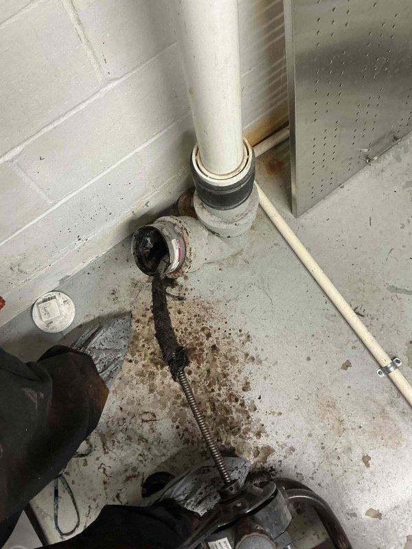 Responded to a main line drainage issue at the property. Upon arrival, inspected the basement utility area where the main sewer line is accessible through the concrete floor. The PVC cleanout pipe was located in the mechanical room near the gas meter and HVAC equipment. Documented existing conditions showing deteriorated flooring with moisture staining and aging infrastructure. Assessed the main line access point and surrounding plumbing connections to determine the scope of the drainage problem. Photographed the cleanout location and adjacent piping system for service records.