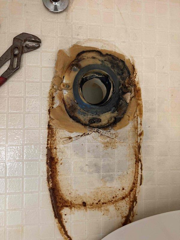 Responded to report of toilet leaking bright orange liquid at base in residential bathroom. Upon arrival, removed toilet to inspect flange and identify source of leak. Found deteriorated wax ring with significant rust-colored staining and corrosion around toilet flange area. Orange discoloration on floor tiles confirmed ongoing water seepage from failed seal. Removed old wax ring, cleaned flange and surrounding area of rust deposits and mineral buildup. Inspected flange for structural integrity and proper mounting. Installed new wax ring and reinstalled toilet, ensuring proper seal and secure mounting to prevent future leaks. Tested flush operation and verified no leakage at base. Explained to homeowner that discoloration was caused by corroded metal components in plumbing system mixing with water, creating the distinctive orange residue observed.