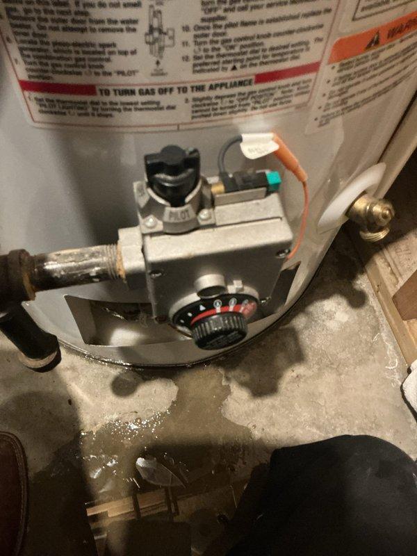 Responded to water heater leak complaint at residential property. Upon arrival, found active water pooling at base of standard atmospheric vent gas water heater. Inspected gas control valve assembly, temperature and pressure relief valve, drain valve, and all threaded connections for source of leak. Confirmed water accumulation in drip pan area beneath unit. Documented leak location and water heater condition with photographs showing gas control valve assembly and overall unit installation. Based on visual inspection and leak pattern, determined tank integrity may be compromised. Advised customer of findings and recommended water heater replacement due to tank failure, as this represents a recurring issue per service history.