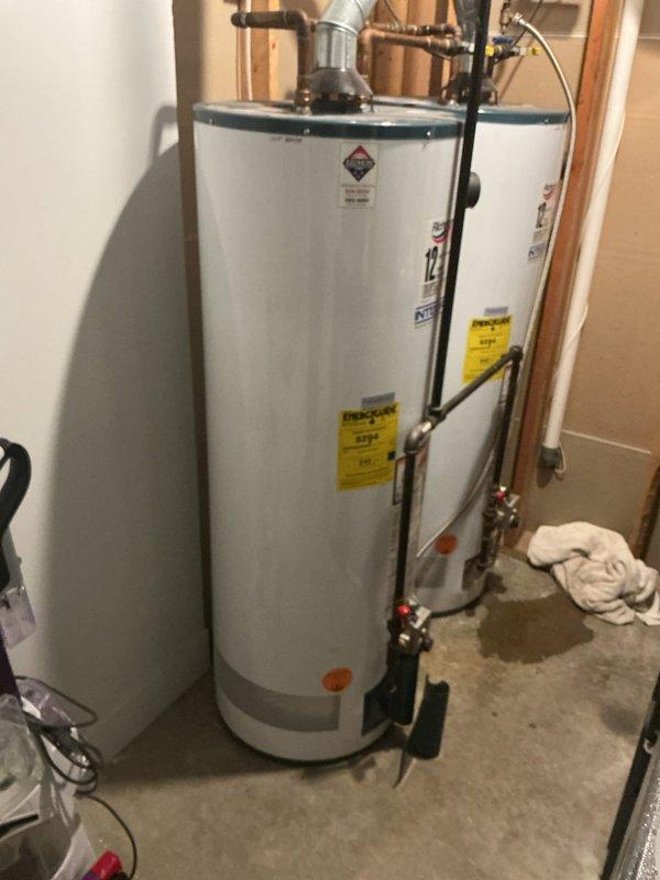 Responded to water heater leak complaint at residential property. Upon arrival, found active water pooling at base of standard atmospheric vent gas water heater. Inspected gas control valve assembly, temperature and pressure relief valve, drain valve, and all threaded connections for source of leak. Confirmed water accumulation in drip pan area beneath unit. Documented leak location and water heater condition with photographs showing gas control valve assembly and overall unit installation. Based on visual inspection and leak pattern, determined tank integrity may be compromised. Advised customer of findings and recommended water heater replacement due to tank failure, as this represents a recurring issue per service history.
