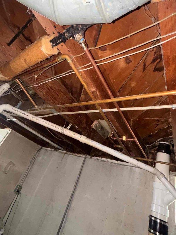 Completed plumbing system repair in basement crawl space area involving copper pipe installation and associated infrastructure work. Addressed water damage concerns visible on foundation surfaces and installed proper pipe mounting and support systems. Work included coordination with existing PVC drainage lines, structural framing modifications, and ceiling cavity access for utility routing to ensure proper integration with building's plumbing infrastructure.