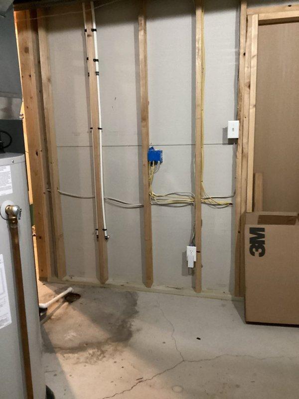 Completed comprehensive plumbing estimate for relocating washer and dryer from main level to basement location. Assessment included evaluating existing basement infrastructure with exposed wall framing, electrical components, and water heater positioning, as well as inspecting current main level plumbing connections under sink cabinet including PVC drainage, supply lines, and available shut-off valves to determine scope of work required for appliance relocation.