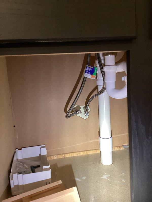 Completed comprehensive plumbing estimate for relocating washer and dryer from main level to basement location. Assessment included evaluating existing basement infrastructure with exposed wall framing, electrical components, and water heater positioning, as well as inspecting current main level plumbing connections under sink cabinet including PVC drainage, supply lines, and available shut-off valves to determine scope of work required for appliance relocation.