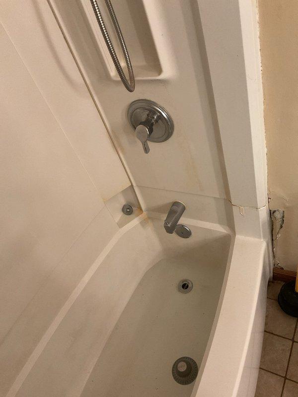 Conducted on-site assessment of leaking plumbing in upstairs bathroom of 70-year-old residential property. Inspected bathtub and shower combination unit, identifying compromised pipe requiring removal and replacement. Documented existing conditions including white tile surround, chrome fixtures, and current plumbing configuration with photographs for estimate preparation prior to commencing repair work.